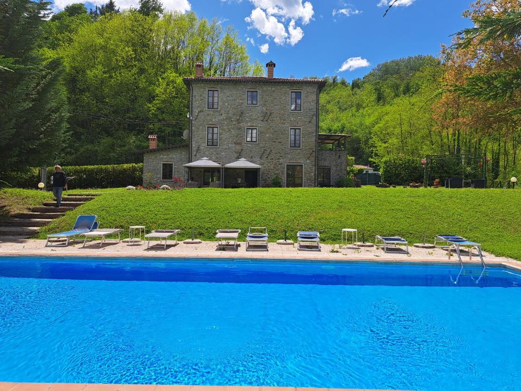 una casa con piscina frente a un edificio en Villa Casa di Pietra en el norte de Lucca, Toscana en Camporgiano