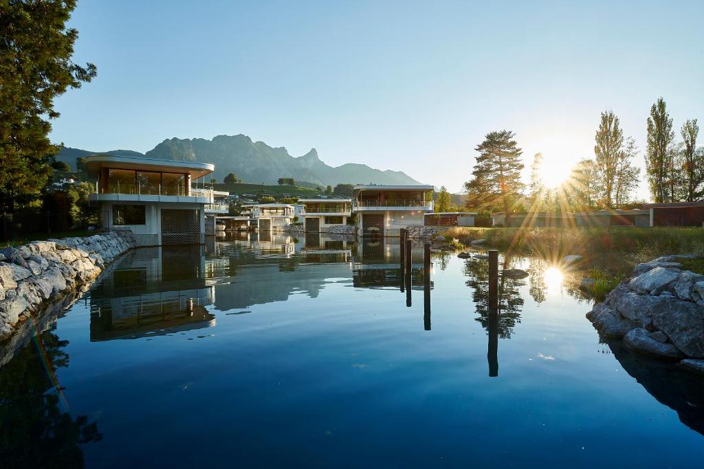 a large body of water with buildings and the sun setting at Deltapark Vitalresort Seevillen in Thun