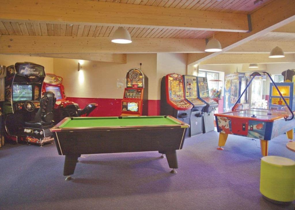 a room with a pool table and arcade games at Sunbeach Holiday Park in Llwyngwril