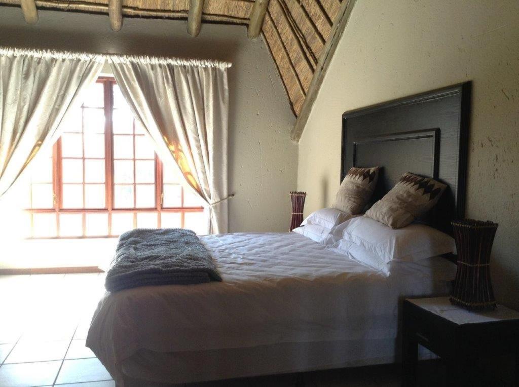 sypialnia z dużym łóżkiem i dużym oknem w obiekcie Matalatala Wildlife Lodge w mieście Roodeplaat