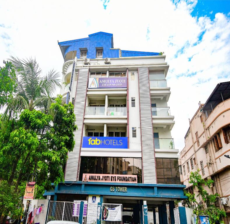 een hoog wit gebouw met een blauw bord erop bij FabHotel Silverkey Kalighat in Calcutta