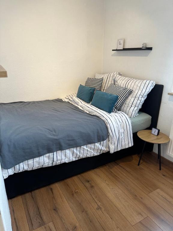 Schlafzimmer mit einem Bett mit blauen Kissen und einem Tisch in der Unterkunft FeWo Lindenallee in Nordhorn