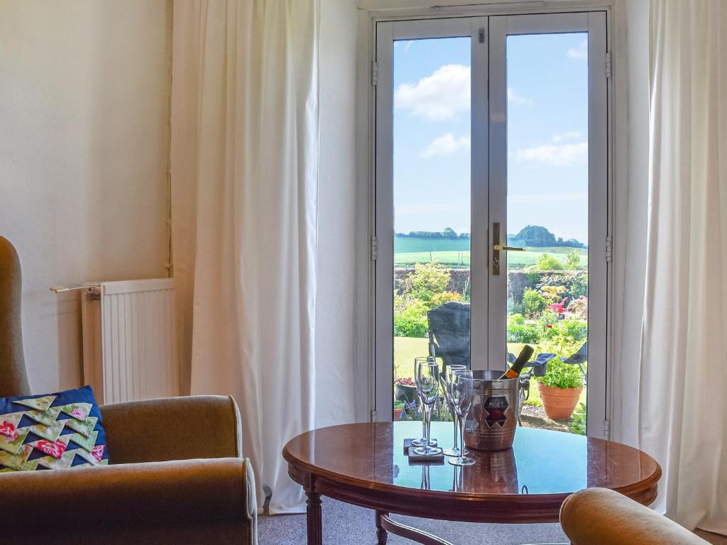 a living room with a table and a glass door at Thornes Farm Annexe in West Quantoxhead