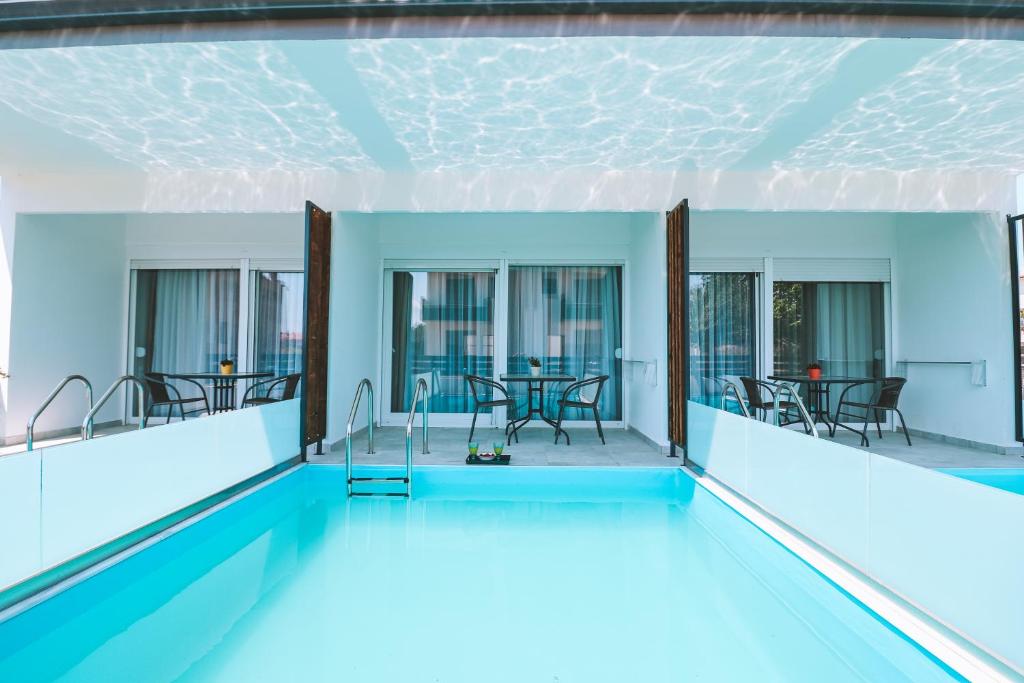 a swimming pool with tables and chairs in a building at Sithon Diamond Suites 2 in Nikiti