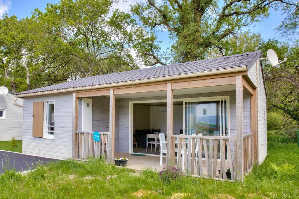 ein kleines weißes Cottage mit einer Veranda in der Unterkunft Escapade entre ocean et foret a Pont-l Abbe in Pont-lʼAbbé