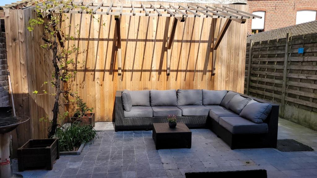 a couch sitting on a patio in front of a wooden fence at Troubadour24 in Poperinge
