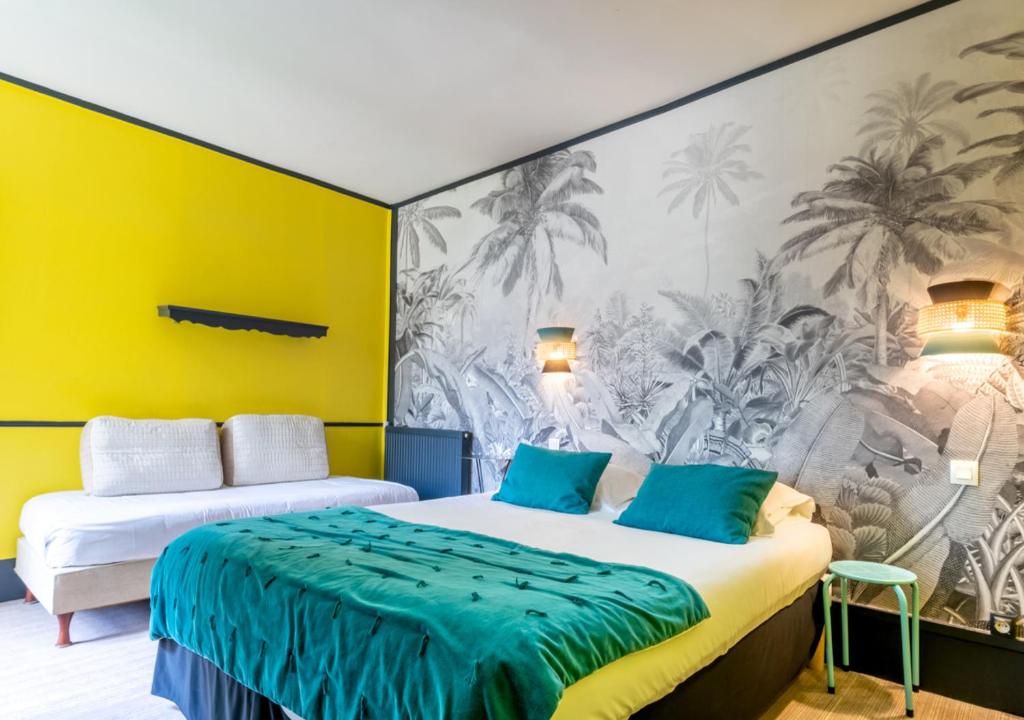 two beds in a room with a yellow wall at Nouvel Hôtel in Paris