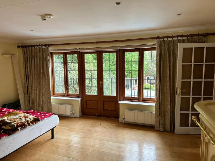 a large room with windows and a bed in it at Maywoods Apartment in Virginia Water