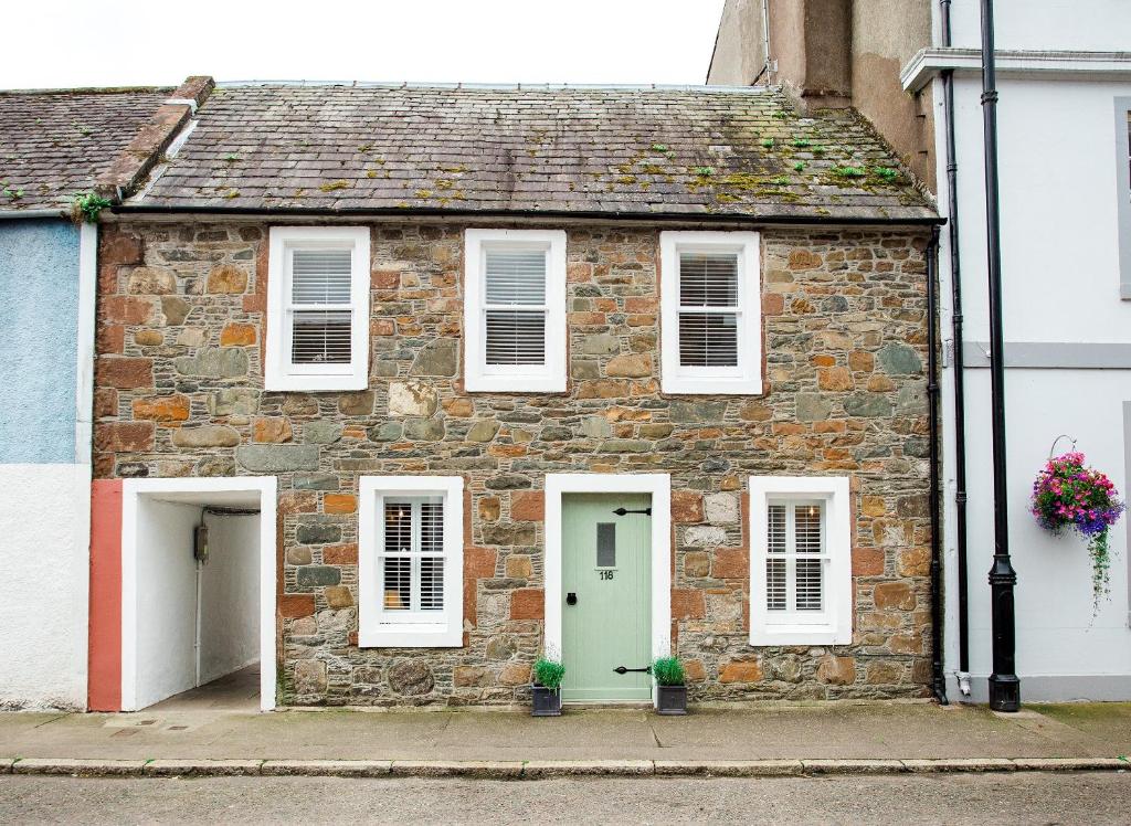 an old brick house with a green door and white windows at 118 High Street in Kirkcudbright