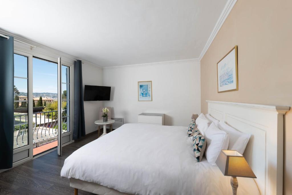 a bedroom with a large white bed and a balcony at Hôtel Beau Site - Cap d'Antibes in Antibes