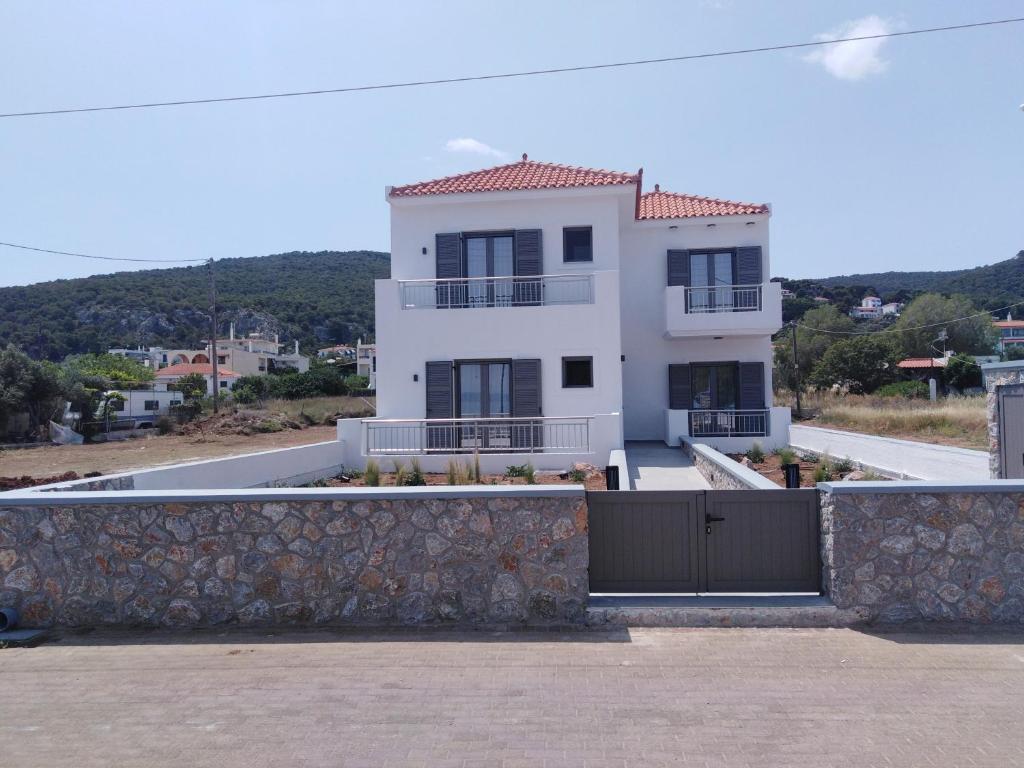 una casa blanca con una valla delante en Agistri Beach, en Skala