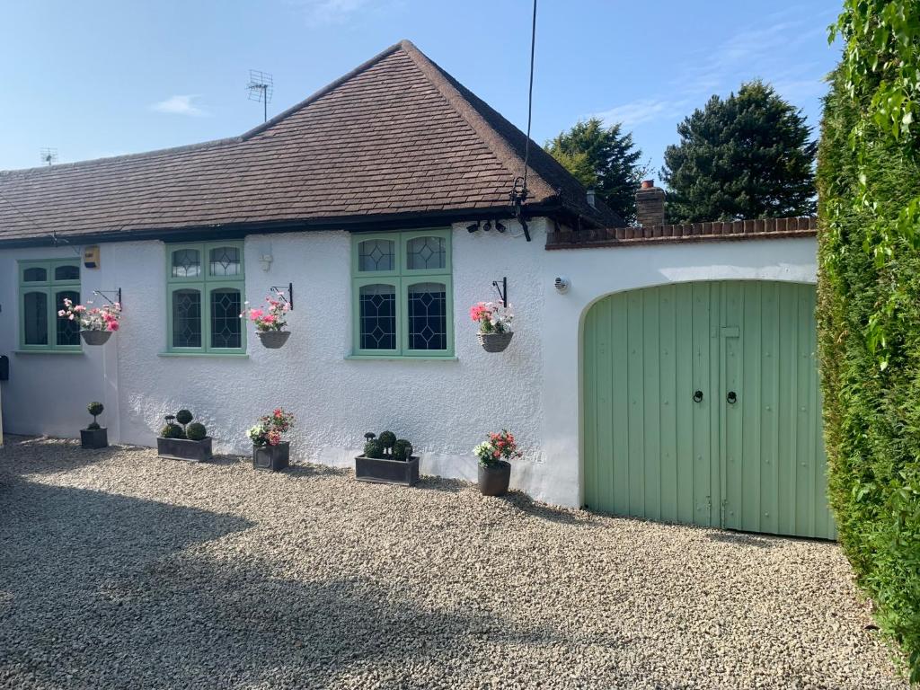 a white house with a green garage at Wychwood A Beautiful Country Style Bungalow in Ash