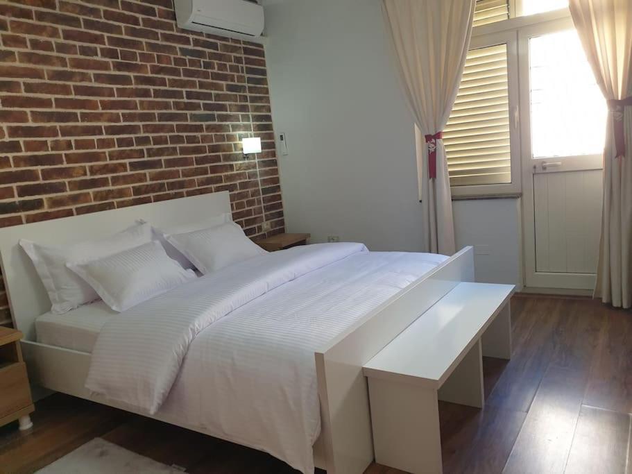 um quarto com uma cama branca e uma parede de tijolos em Shkodra 27 center house em Shkodër