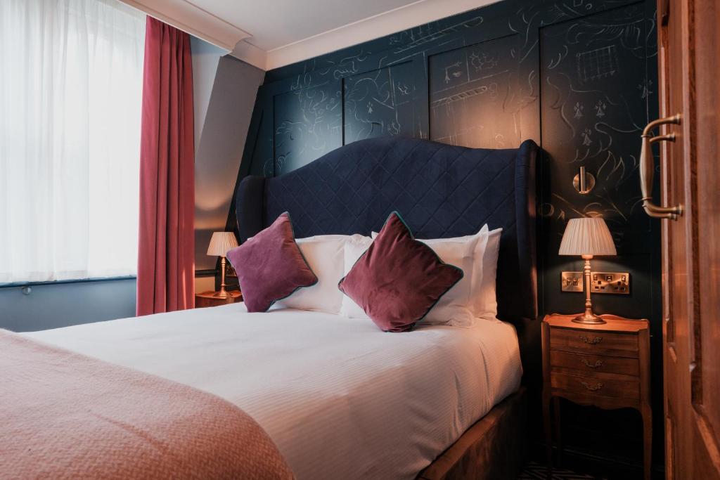 1 dormitorio con 1 cama grande con almohadas moradas en The Sanctuary House Hotel, en Londres
