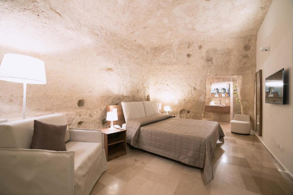 een slaapkamer met een bed en een bank bij Albergo Del Sedile in Matera