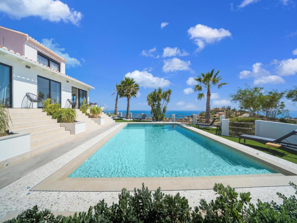 a swimming pool in front of a house with the ocean at Belvilla by OYO La Sirena in Carrer del Mar