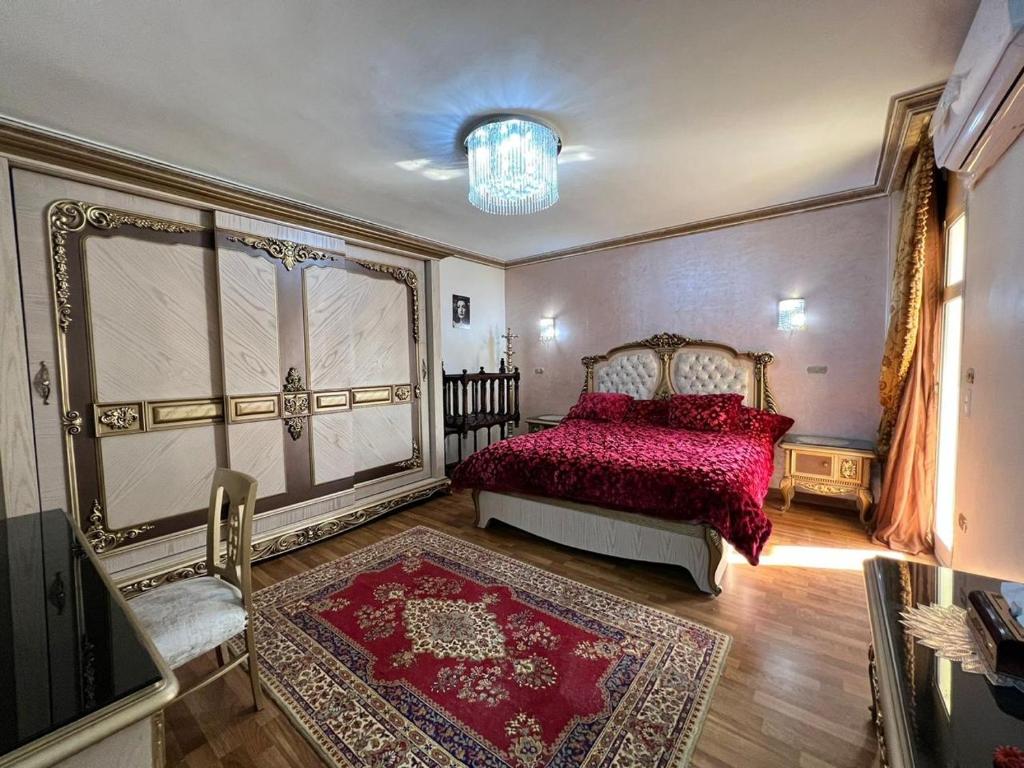 a bedroom with a red bed and a chandelier at شقه سكنيه فى مدينتى in Madinaty