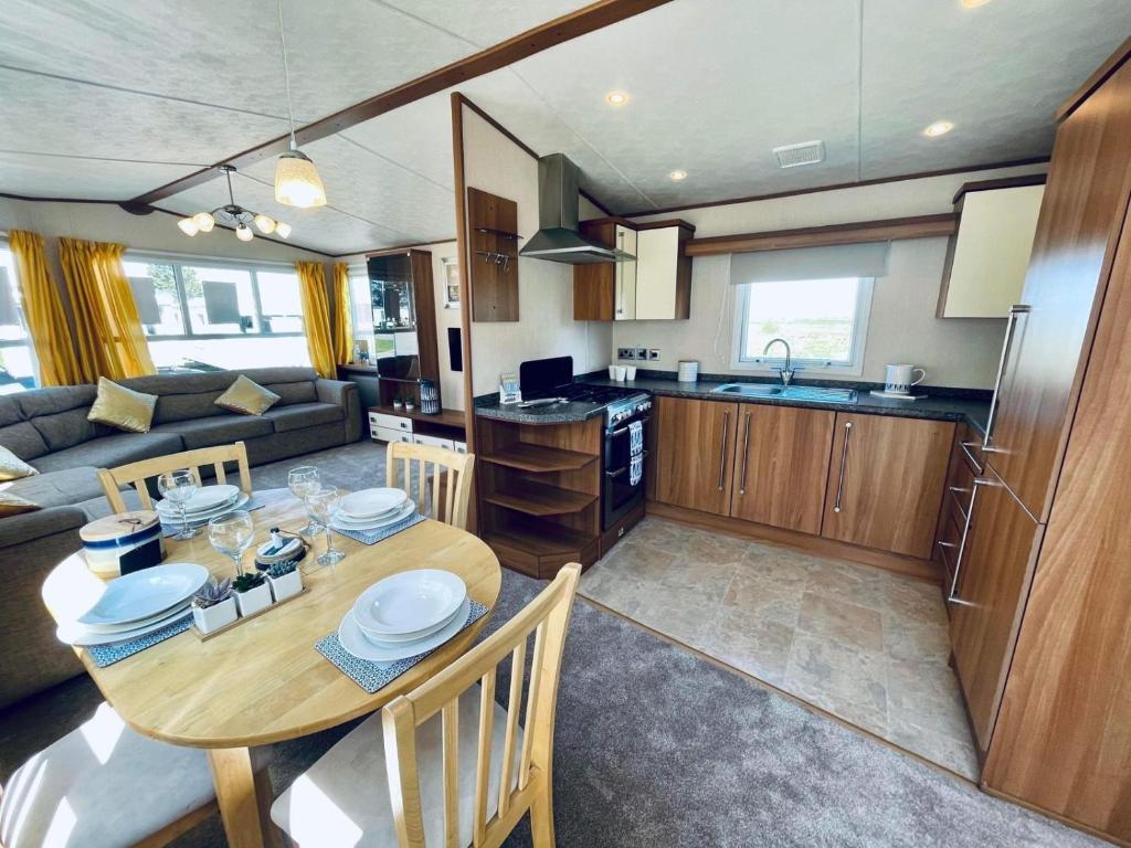uma cozinha e sala de estar com uma mesa de madeira e cadeiras em Superb Caravan At Steeple Bay Holiday Park In Essex, Sleeps 6 Ref 36081d em Southminster