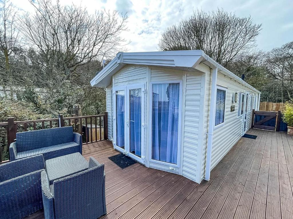 a white house on a deck with two chairs at Modern Caravan With Decking At Azure Seas Along The Suffolk Coast Ref 32065az in Lowestoft