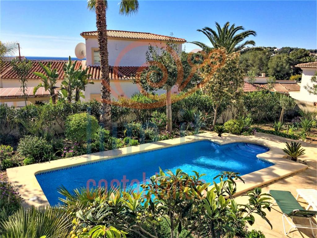 a swimming pool in front of a house with palm trees at CASA BACANA. MORAIRA- LIVE IT COSTABLANCA in Moraira