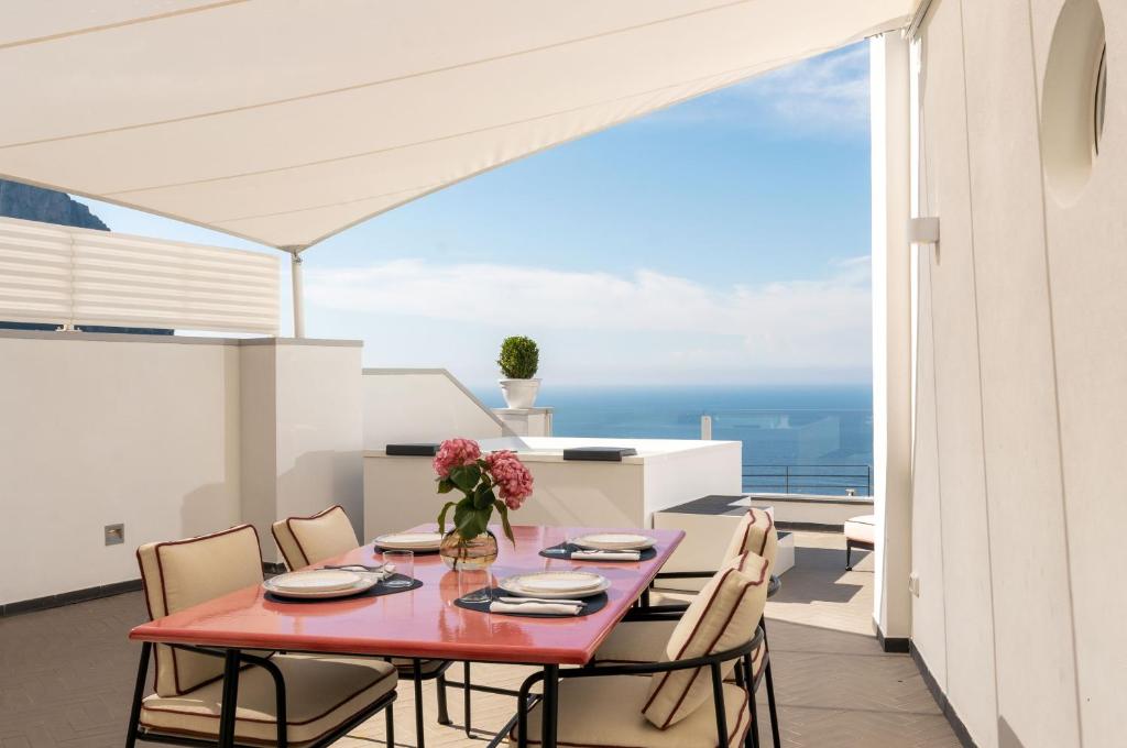 Palazzo M Capri في كابري: غرفة طعام مع طاولة حمراء وكراسي على شرفة