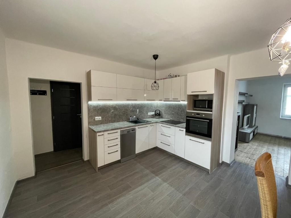 a kitchen with white cabinets and stainless steel appliances at Apartmán SUŠICE 