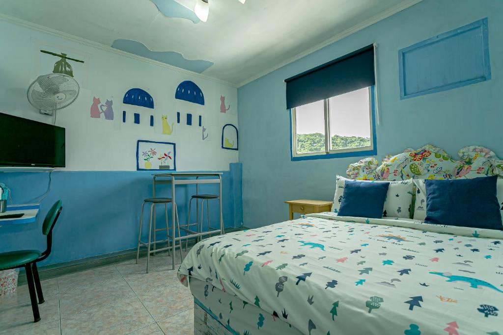 a blue bedroom with a bed and a desk at Evening Sun B&amp;B in Green Island