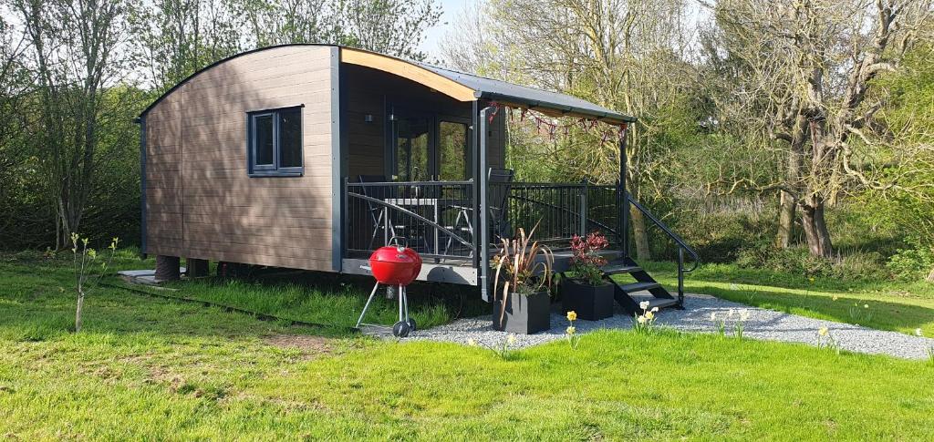 um pequeno barracão com um parque infantil na relva em Peppercorn Pod at Beck House Glamping em Salmonby