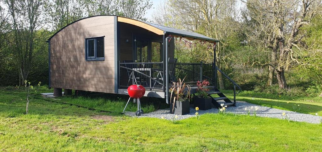 un piccolo capanno con un parco giochi nell'erba di Peppercorn Pod at Beck House Glamping a Salmonby