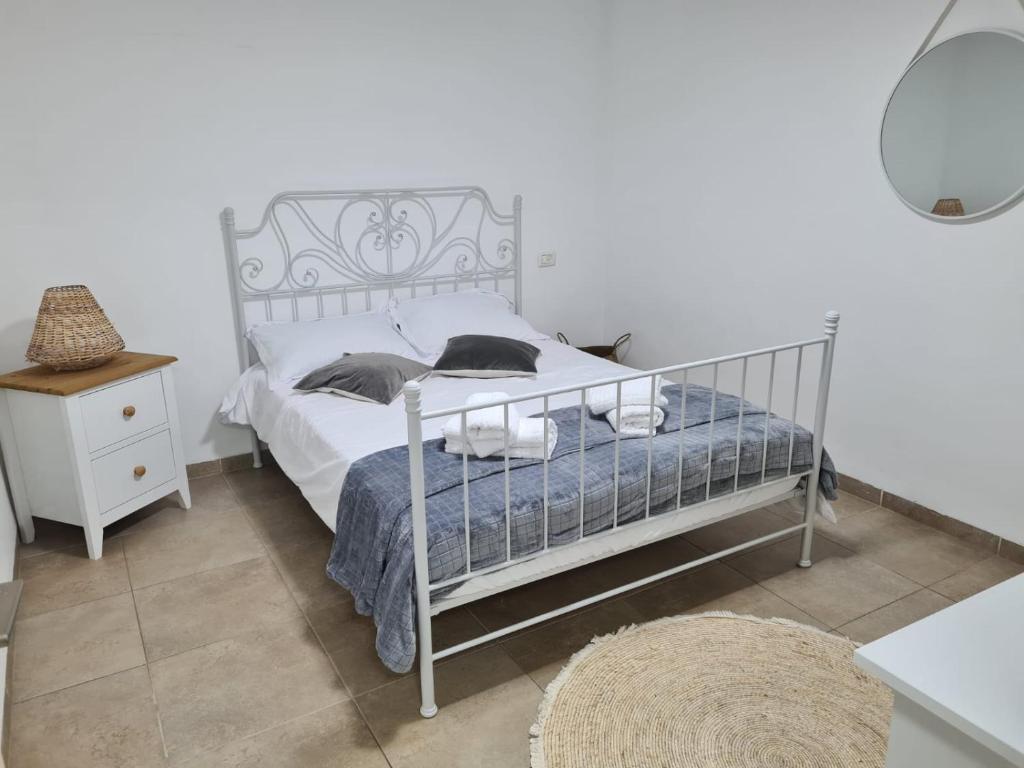 1 dormitorio con cama blanca y mesita de noche en חלומות סיגלית בקריית שמונה, en Kiryat Shemona