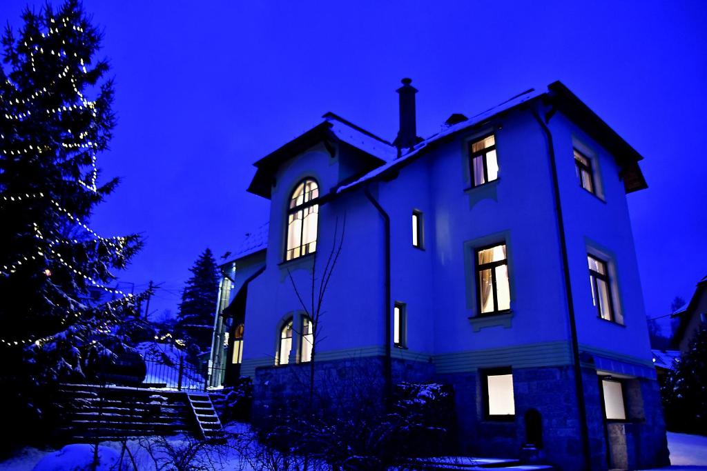 a blue house with its lights on and a christmas tree at Vila Stecker - Zámeček pod Špičákem in Tanvald