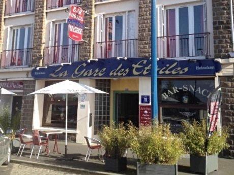 una cafetería con sillas y una sombrilla frente a un edificio en Hotel Moderne, en Vire