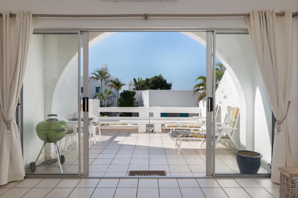 Une porte ouverte s'ouvre sur une terrasse offrant une vue sur l'océan. dans l'établissement Santorini Thira 38 - Family Only, à Ballito