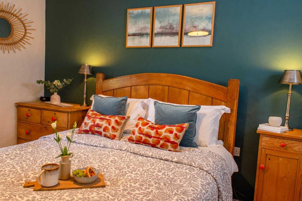Una cama con almohadas y una bandeja de fruta. en Bosinver Farm Cottages Buddleia en St Austell