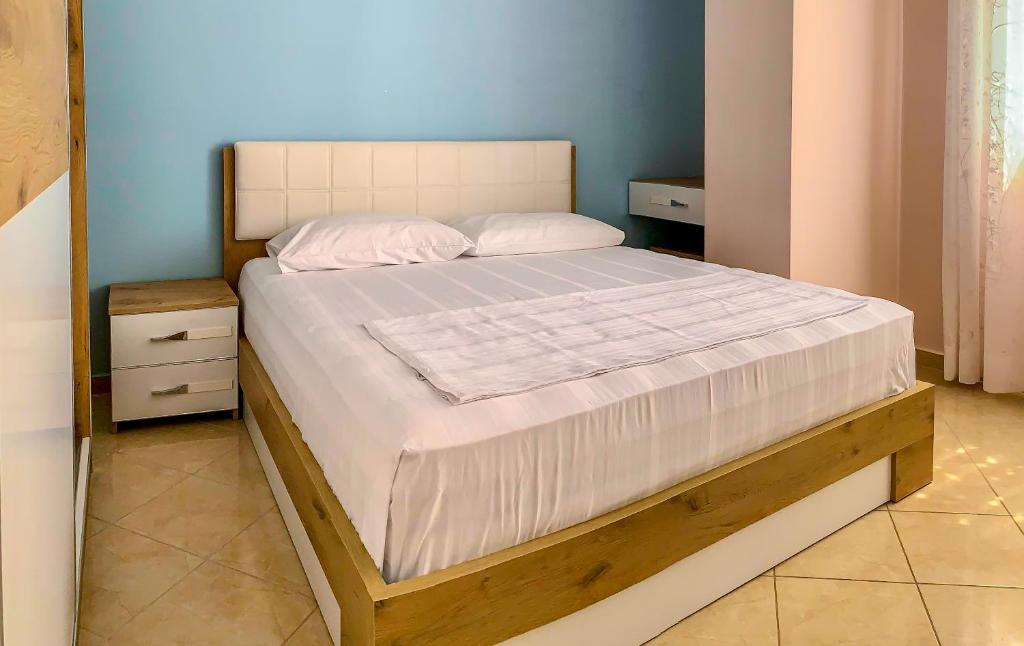 sypialnia z dużym łóżkiem z drewnianą ramą w obiekcie Endy Apartaments w mieście Orikum