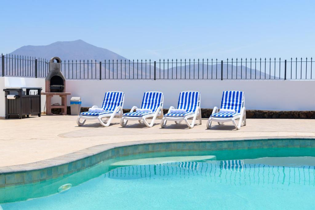 4 sillas azules y blancas sentadas junto a una piscina en Villa Linda, en Playa Blanca