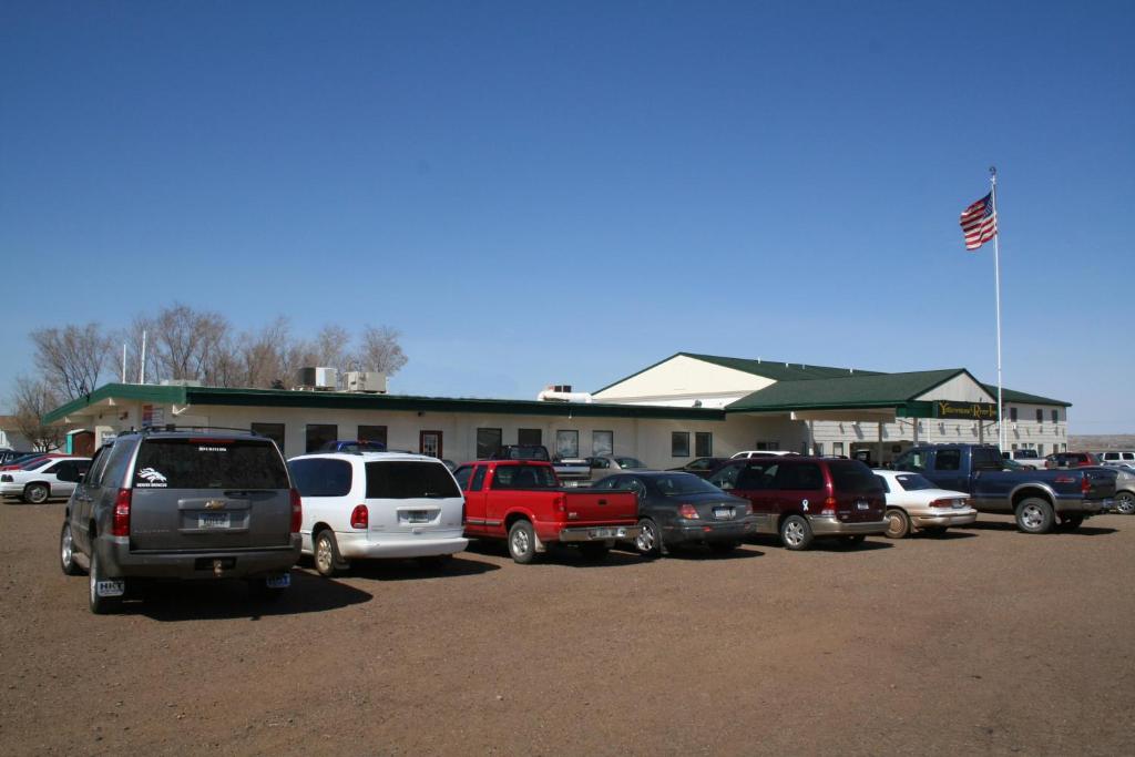 a parking lot with cars parked in front of a building at Yellowstone River Inn in Glendive