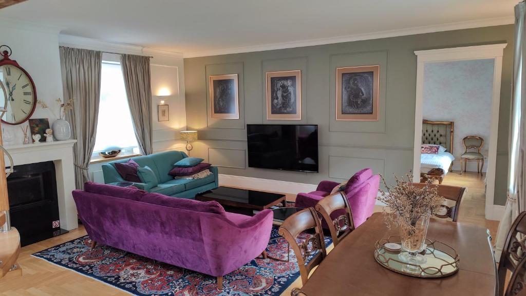 ein Wohnzimmer mit lila Möbeln und einem Fernseher in der Unterkunft Royal Jono st. Apartment in Klaipėda