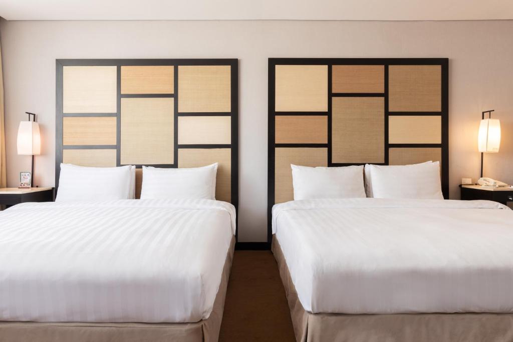 two beds in a hotel room with white sheets at Beitou Sweet Me Hot Spring Resort in Taipei