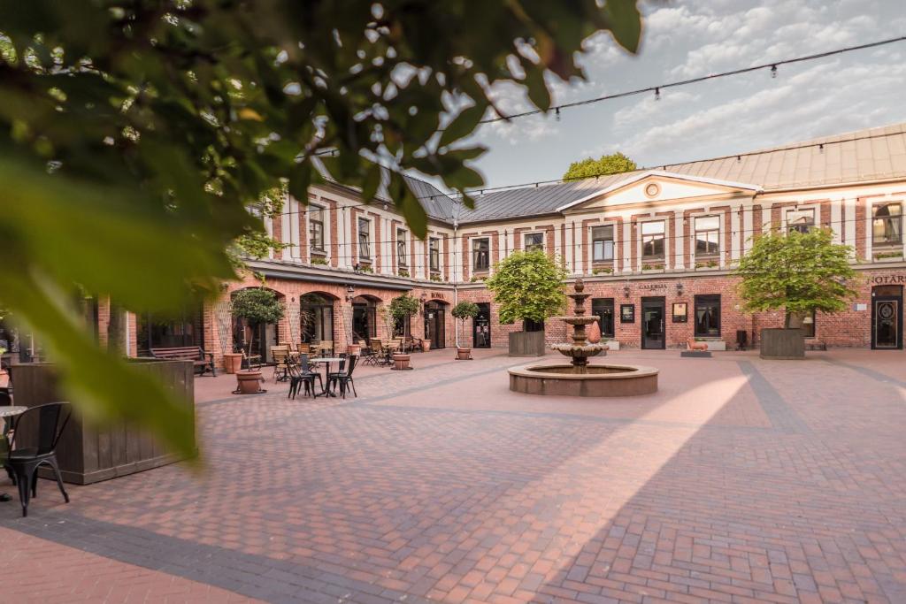 un bâtiment avec une cour agrémentée de tables et d'arbres dans l'établissement Art Hotel Roma, à Liepāja