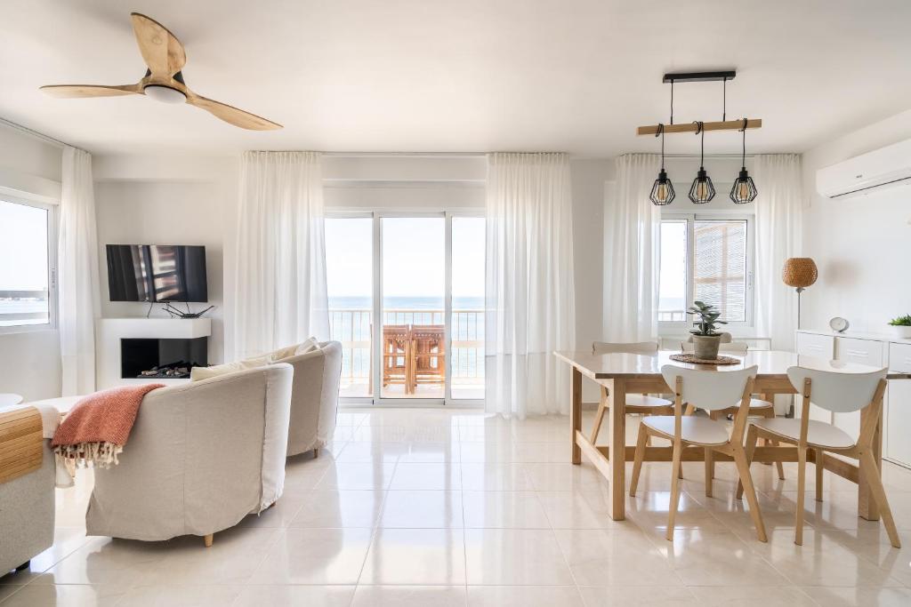 a white living room with a table and chairs at El Acuario - Primera línea y todas las ventanas dan al mar in Cullera