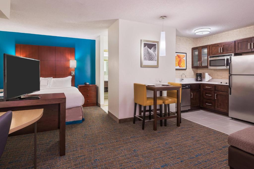 サバンナにあるResidence Inn Savannah Midtownのベッド、デスク、キッチンが備わるホテルルームです。