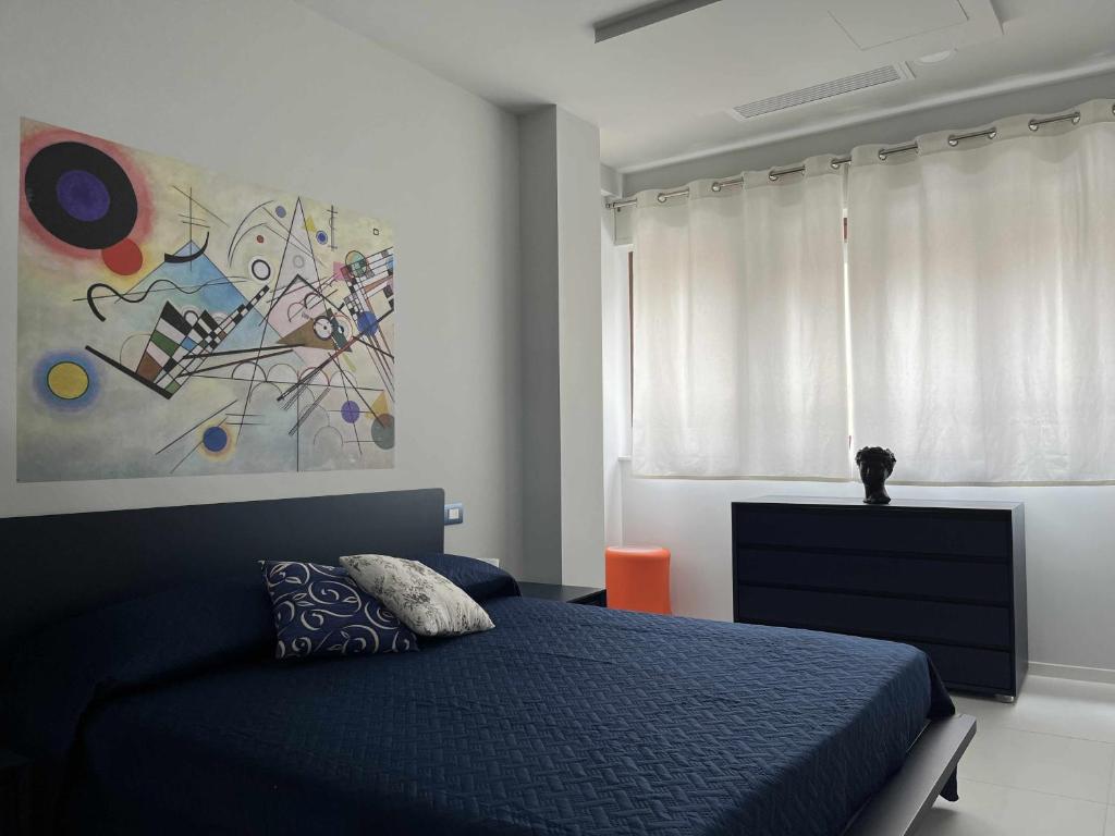 a bedroom with a blue bed and a painting on the wall at Casaincentro civitanova in Civitanova Marche