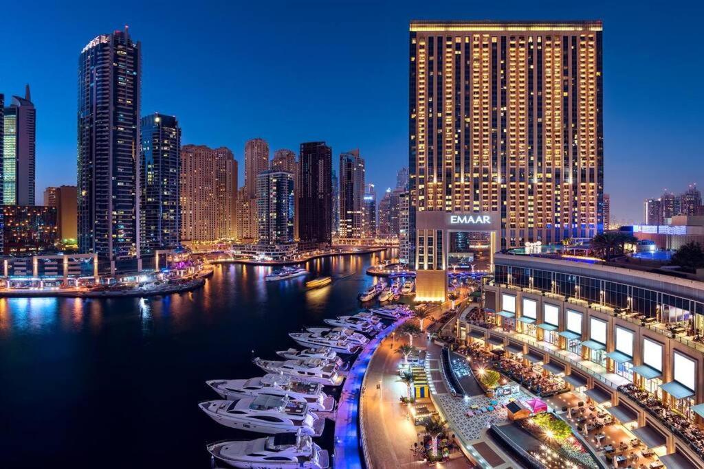 a city skyline with boats in the water at night at Spacious, Modern Studio in Marina Dubai in Dubai