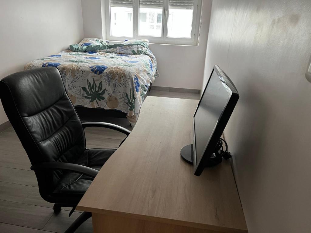 Zimmer mit einem Schreibtisch, einem TV und einem Bett in der Unterkunft Appartement près de La défense in Nanterre