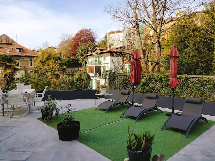 eine Terrasse mit Stühlen, Sonnenschirmen und Gras in der Unterkunft Doma Etxea Donostia-San Sebastian in San Sebastián