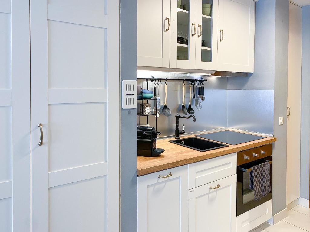 a kitchen with white cabinets and a sink at swissme - modernes Studio mit Balkon & Parkplatz & Netflix in St. Moritz