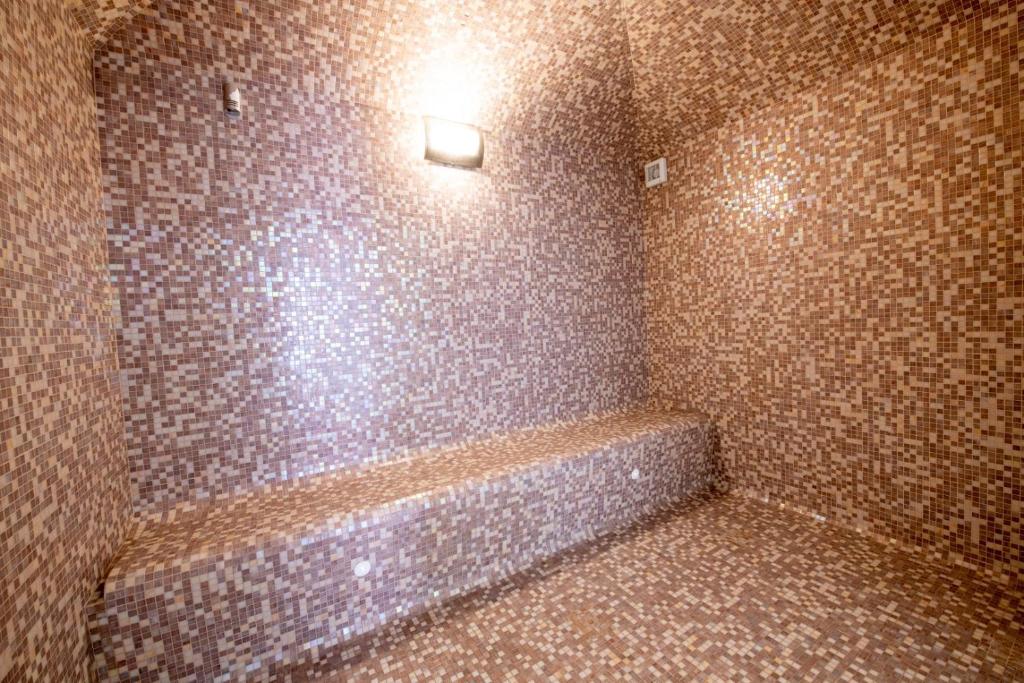 a tiled bathroom with a tub and a light on the wall at Mar da Luz Resort in Luz