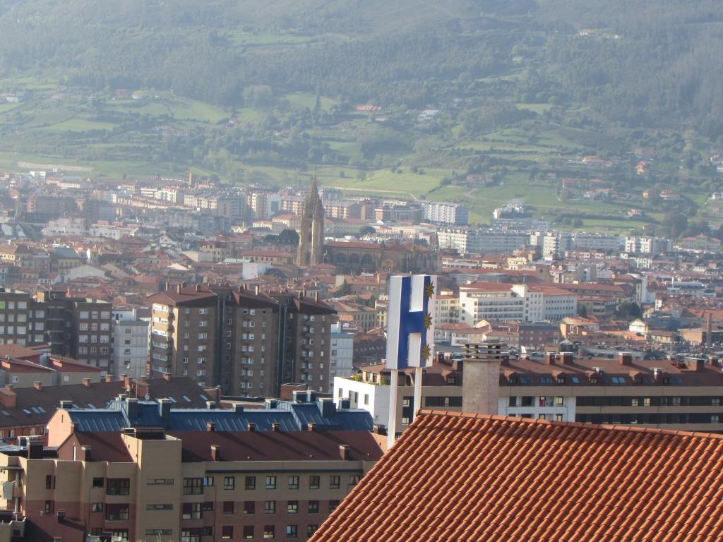 vistas a una ciudad con edificios y montañas en Hotel Palacio de Asturias, en Oviedo