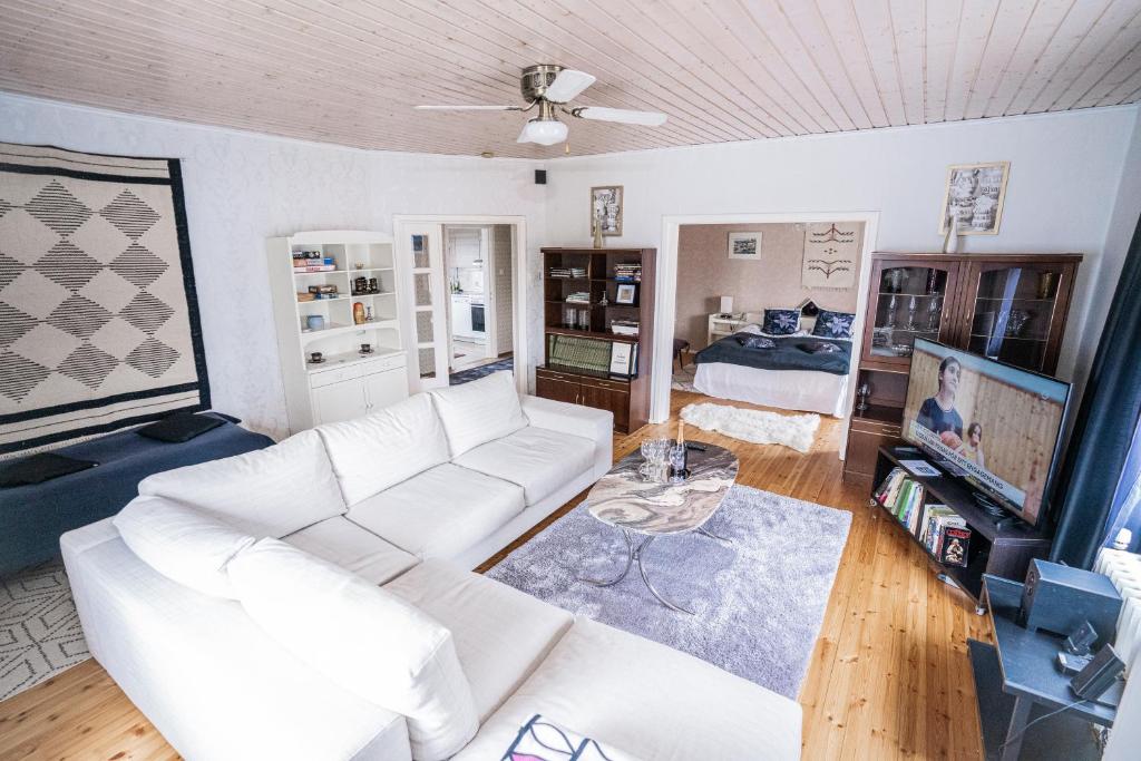sala de estar con sofá blanco y TV en Iso ja viihtyisä asunto Pietarsaaressa, en Jakobstad